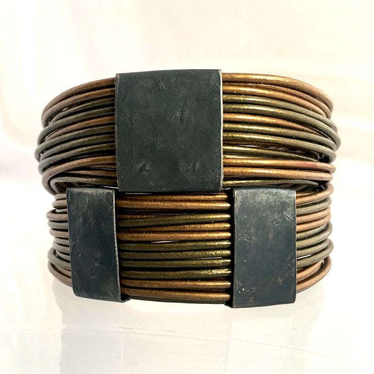 a close up of a metal bracelet on a white surface with black square magnets