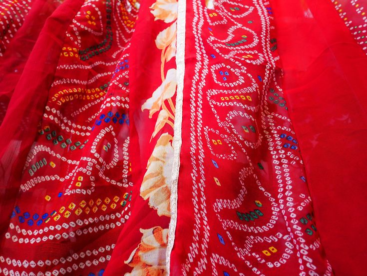 closeup of red fabric with white and blue designs on it, in the sunlight