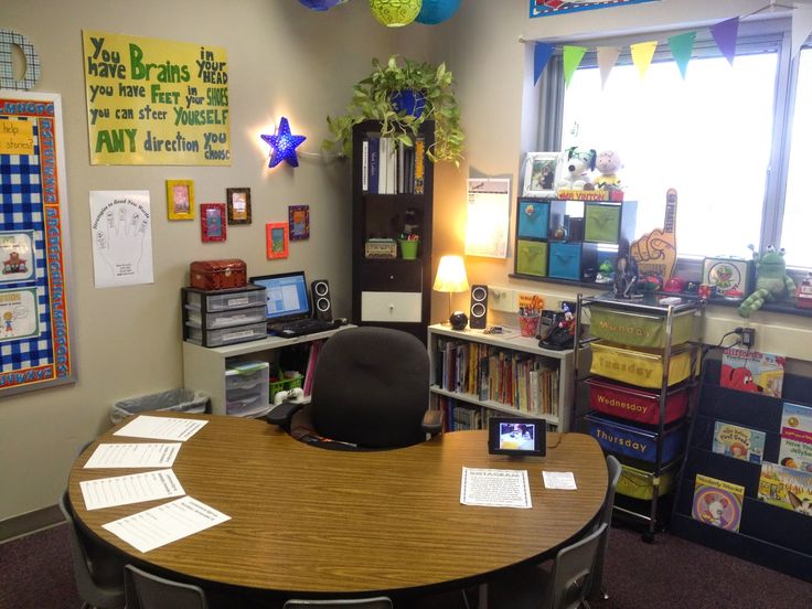 a classroom with desks, bookshelves and posters on the wall