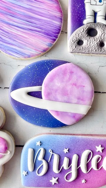 some cookies that are on top of a white table with purple and blue icing