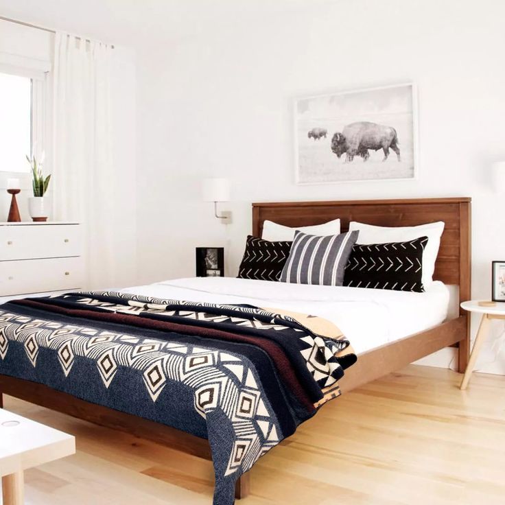 a bedroom with white walls and wood flooring has a large bed in the center