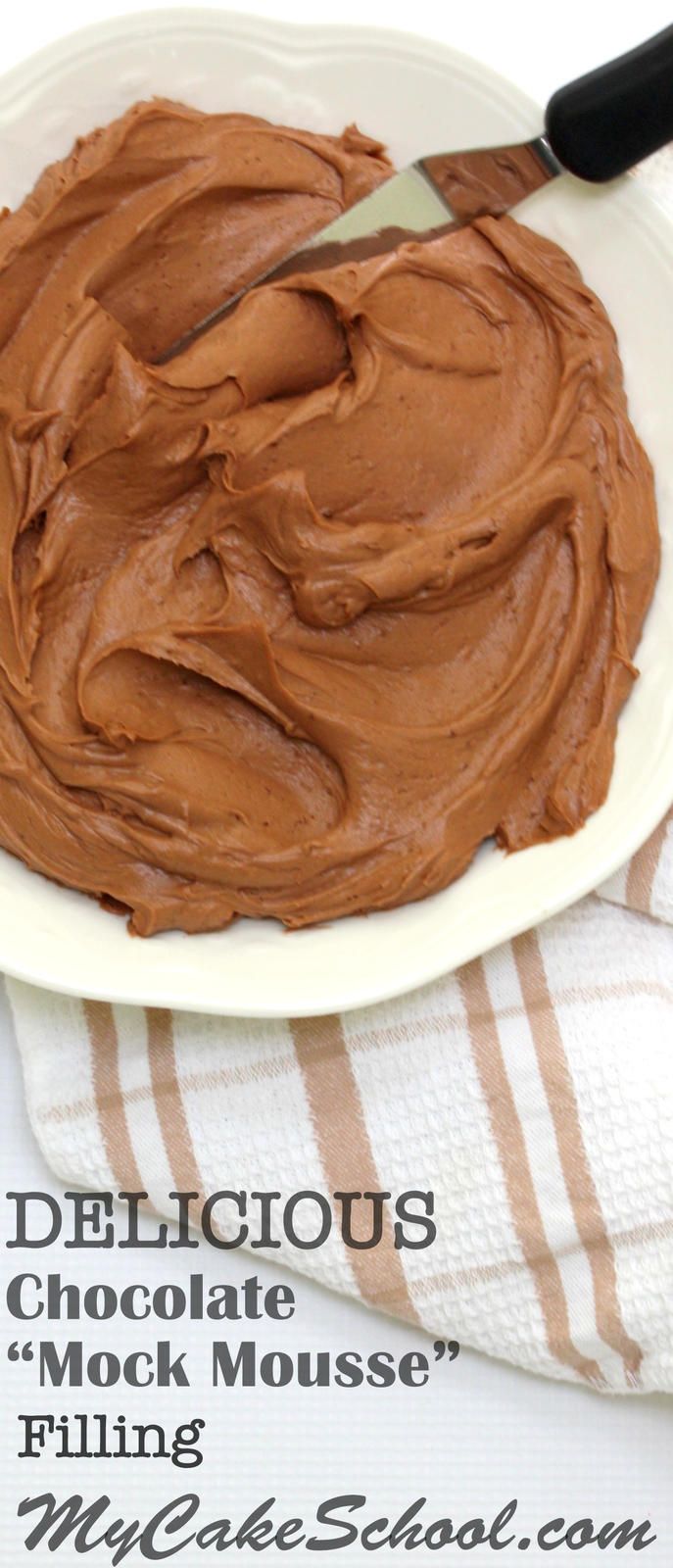 a white plate topped with chocolate frosting on top of a striped towel next to a knife