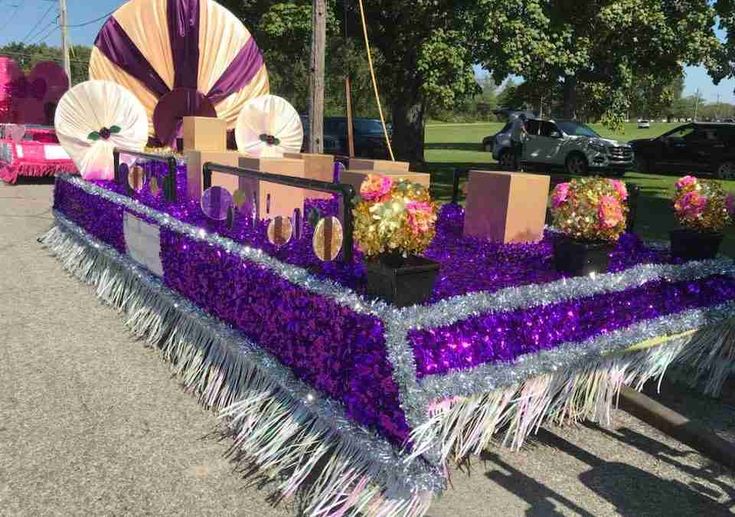 a table with purple and white decorations on it in the middle of a parking lot