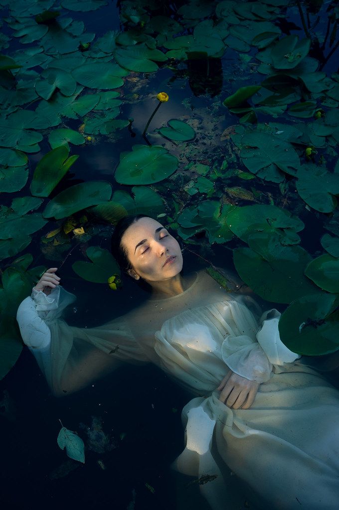 a woman floating in the water surrounded by lily pads