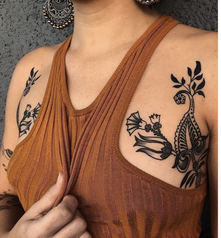 a woman with some tattoos on her chest and arm is holding something in her hand