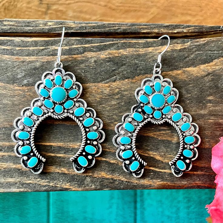 These In Full Bloom Blossom Earrings are crafted from high polish silver in a western concho style. The textured squash blossom design features genuine turquoise stones and a fish hook dangle for a unique, eye-catching look. Perfect for any occasion. Southwestern Concho Earrings For Festivals, Handmade Western Turquoise Earrings, Southwestern Teardrop Concho Earrings, Turquoise Dangle Earrings Western Style, Western Turquoise Dangle Earrings, Turquoise Nickel-free Western Earrings, Western Turquoise Nickel-free Earrings, Western Style Turquoise Nickel-free Earrings, Western Style Nickel-free Turquoise Earrings