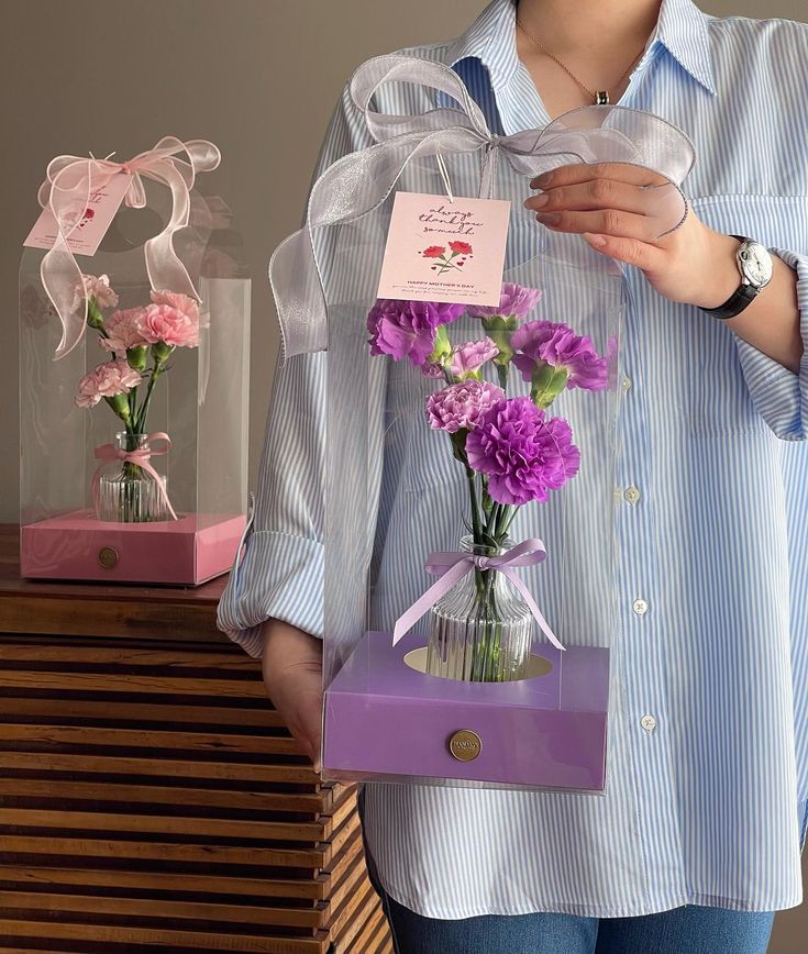 a woman holding a vase with flowers in it and a note attached to the top