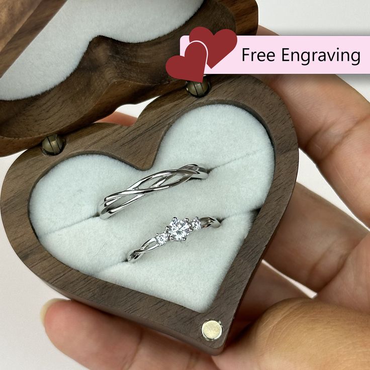 someone is holding a heart shaped box with two engagement rings in it and the ring holder has been made out of wood