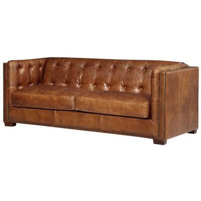 a brown leather couch sitting on top of a white floor