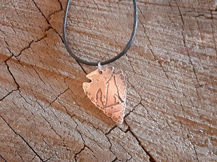 handmade and rustic copper arrowhead necklace with a howling coyote on one side and a hammered texture on the other side adjustable black leather cord with slip knots the arrow head is 1.5 inch by 1 inch in size with a thickness of 1 mm perfect gift or something for yourself Adjustable Silver Arrowhead Necklace, Silver Adjustable Arrowhead Necklace, Adjustable Hand Forged Brown Necklace, Adjustable Hand Forged Copper Necklace, Adjustable Copper Hammered Necklace, Adjustable Hammered Copper Necklace, Rustic Hand Forged Adjustable Jewelry, Rustic Adjustable Hand Forged Jewelry, Adjustable Arrowhead Necklace Gift