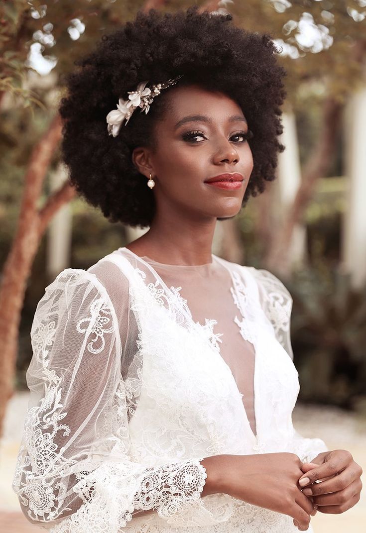 a woman with an afro wearing a white dress and flower in her hair is posing for the camera