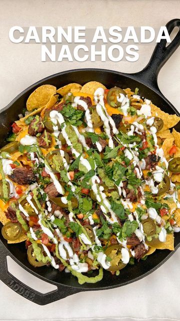 a cast iron skillet filled with nachos covered in sour cream and toppings