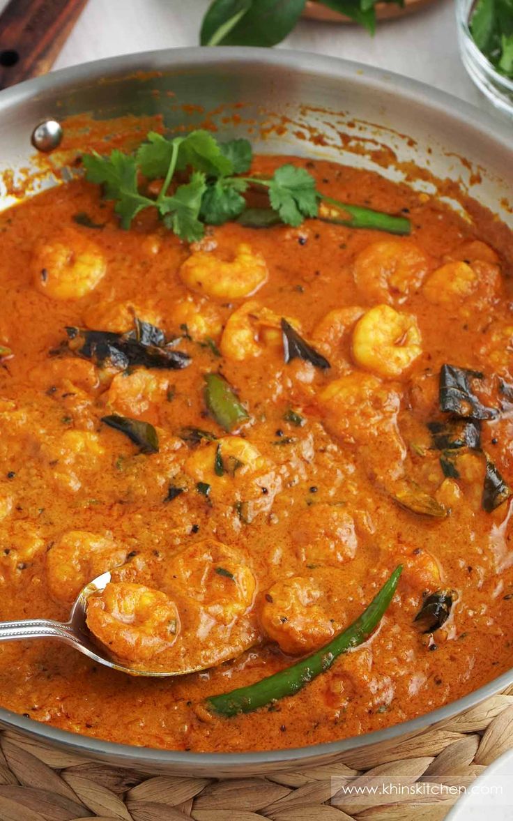 a bowl filled with shrimp and sauce on top of a table