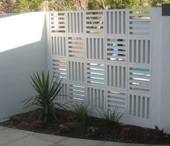 a white fence with vertical slats on the top and bottom, next to a small plant