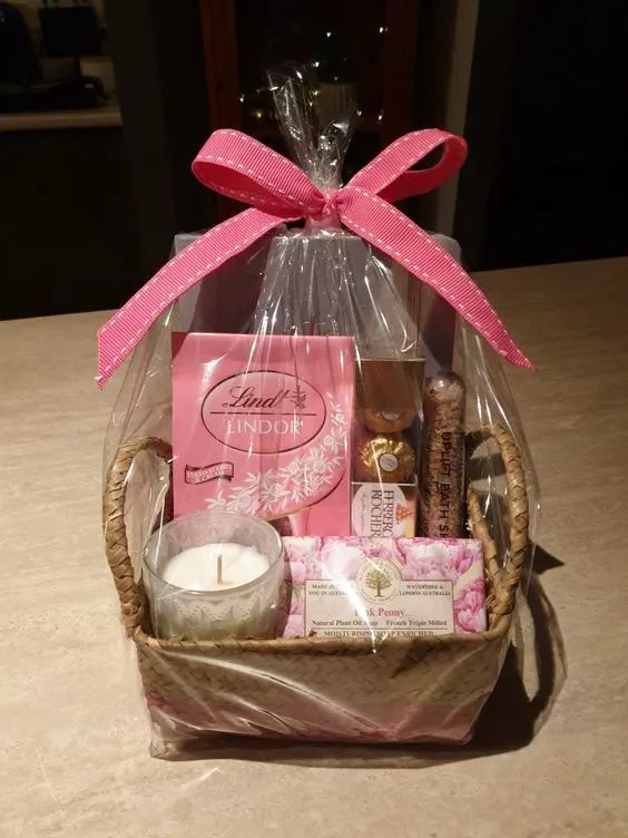 a basket filled with lots of goodies on top of a wooden table next to a candle