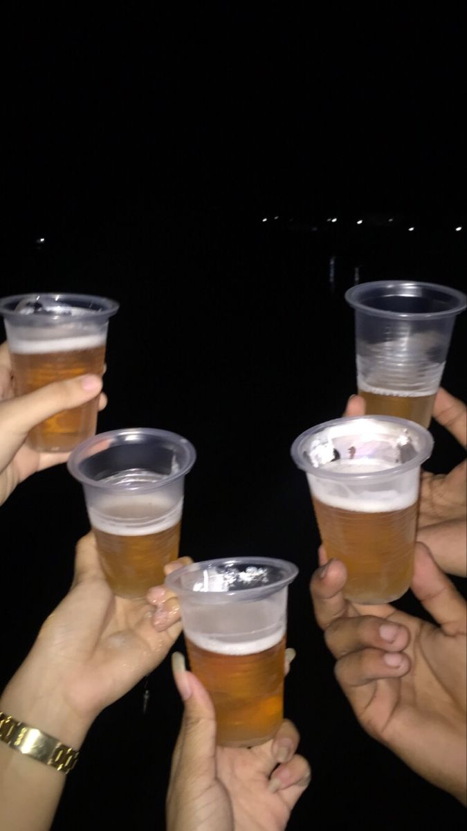 several people are holding up cups with drinks in them and toasting at the same time