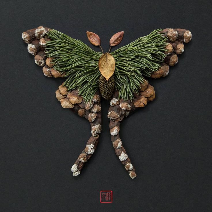 a piece of art made out of pine cones and acorns on a black surface