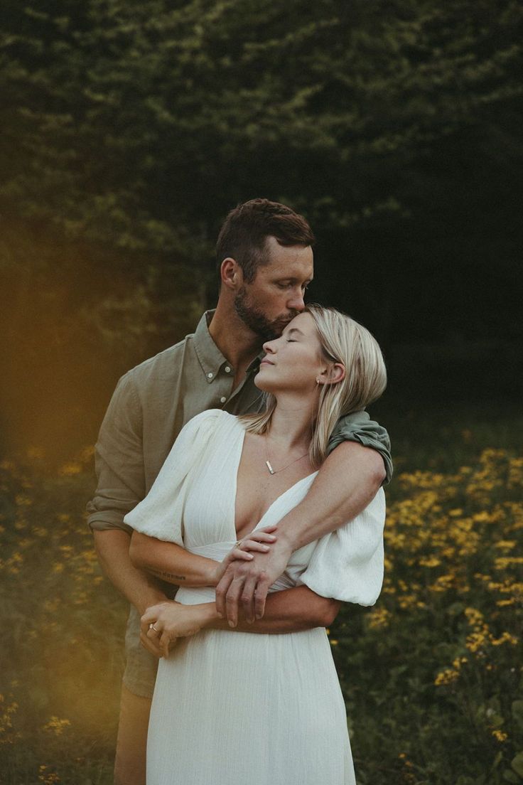 a man and woman embracing each other in the middle of a field with yellow flowers