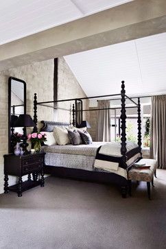 a bedroom with a four poster bed, dresser and mirror on the wall next to it