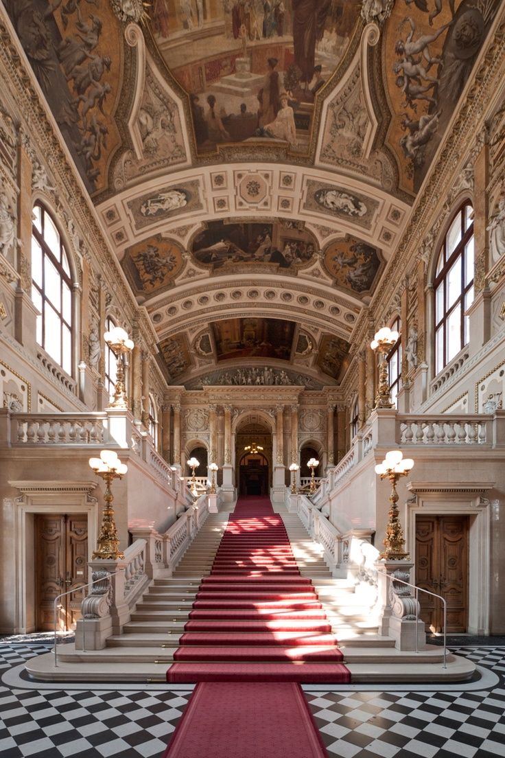 an ornate hallway with red carpet and stairs