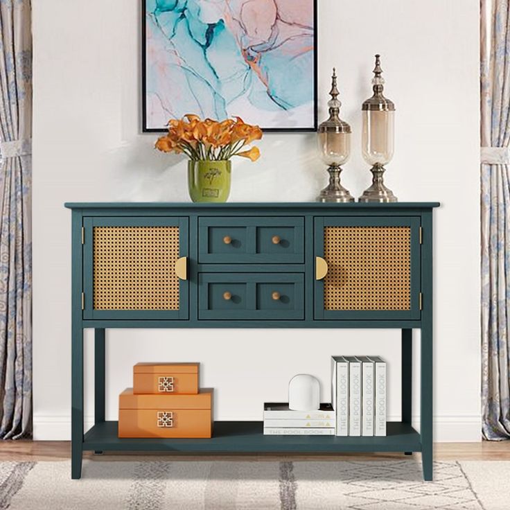 a blue sideboard with wicker doors and drawers next to a painting on the wall