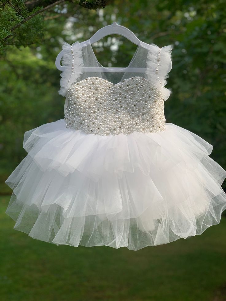 "The listing color is OFF WHITE! You can choose \"White\" when you order. First birthday dress Baby dress Embroidery pearls dress Girl dress Birthday baby dress Dress with pearls Puffy tulle baby dress Wedding baby dress Flower girl dress Toddler dress Princess dress Dress with pearls Puffy baby dress Birthday girl dress Short baby dress Baby birthday dress Dress with feathers Some sizes are READY TO SHIP, Please contact for further information Handmade Pearl Dress with Tutu Skirt Hand beaded wi Sleeveless Ruffled First Communion Dress For Pageant, Sleeveless Ruffled First Communion Dress For Pageants, Sleeveless First Communion Dress With Ruffles For Pageant, White Embellished Princess Dress, Sleeveless Ruffled Tutu Dress For First Communion, White Ruffled Pageant Dress For First Communion, White Princess Pageant Dress With Ruffles, Princess Dresses With Pearl Embroidery For Pageant, Party Princess Dress With Pearl Embroidery And Tulle