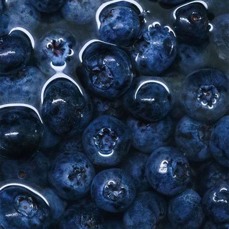 some blueberries are sitting together in the water and they look like they have been washed