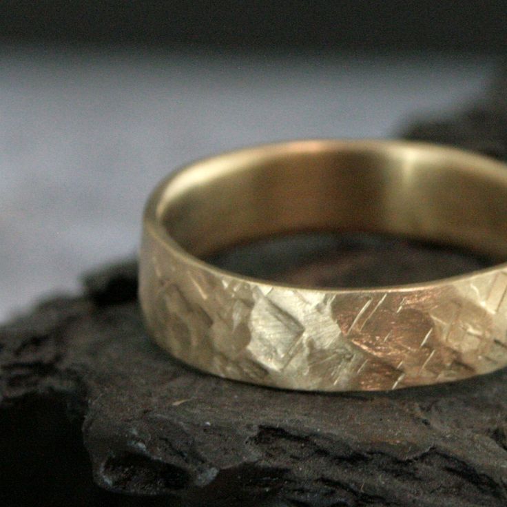 a gold wedding ring sitting on top of a rock