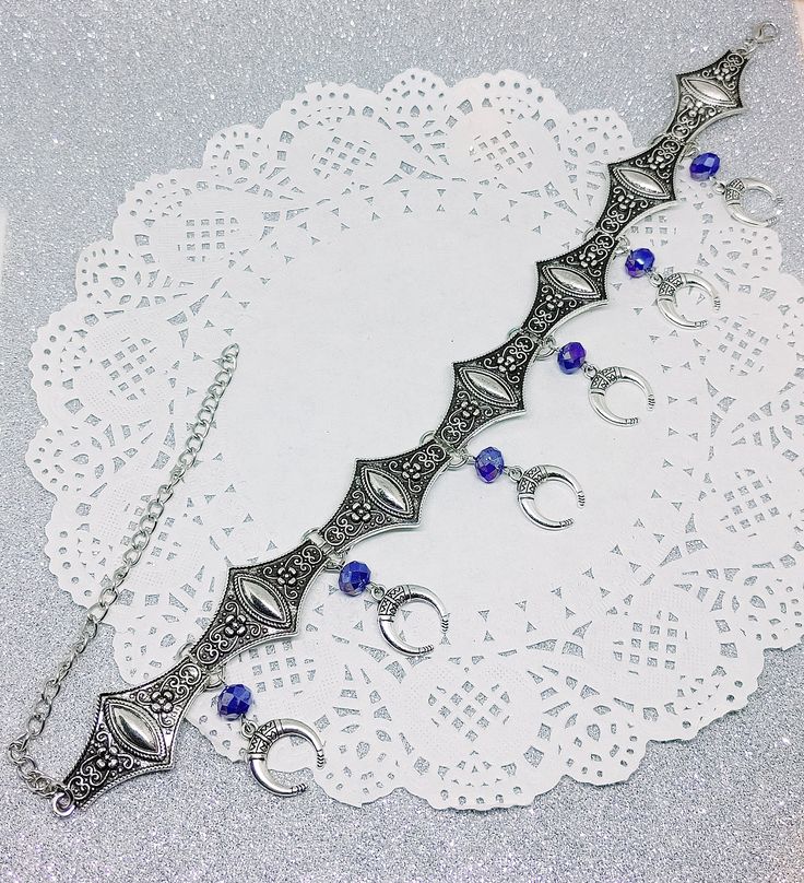 Victorian Gothic metal choker with crescent moon charms and blue crystal beads, ornate metal necklace, Victorian jewelry, Gothic jewelry A beautifully ornate gothic silver metal choker with Victorian crescent moon charms and blue faceted crystal beads. It measures approx. 11 inches in length and has lobster clasp fastening and an extension chain, so that it can be adjusted to fit the neck. The choker is made up of 7 silver toned metal ancient style sections that have intricate detailing. A marve Gothic Blue Metal Jewelry, Crescent Metal Jewelry For Festivals, Metal Crescent Jewelry For Festivals, Blue Gothic Metal Jewelry, Metal Crescent Shaped Festival Jewelry, Crescent-shaped Metal Jewelry For Festivals, Blue Festival Jewelry With Moon Charm, Festival Blue Jewelry With Moon Charm, Festival Jewelry With Blue Moon Charm