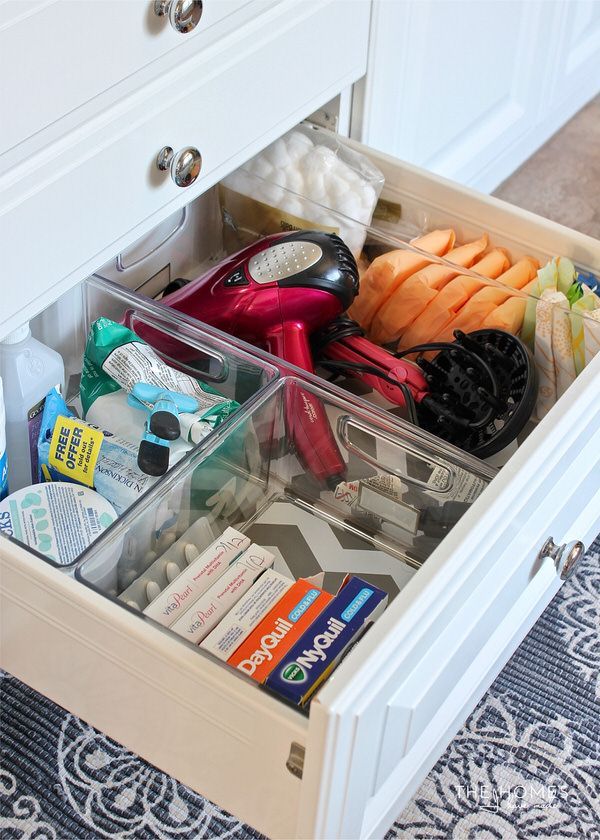 an open drawer with various items in it on a carpeted floor next to white cabinets