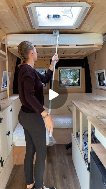 a woman is standing in the back of a small rv with her hand on the door handle