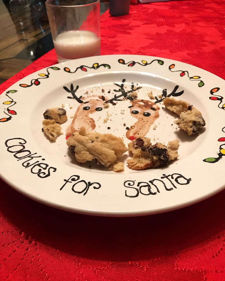 a white plate topped with cookies on top of a red table cloth next to a glass of milk