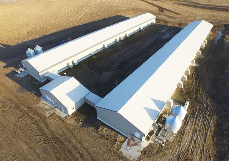 an aerial view of a large white building in the middle of a field with trees