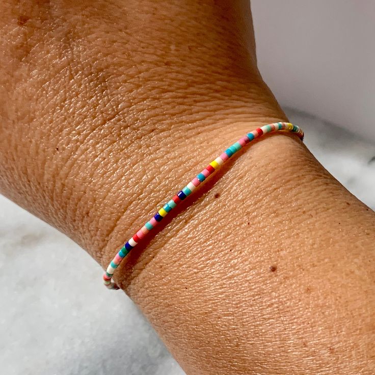 a woman's arm with a colorful beaded bracelet on top of her wrist