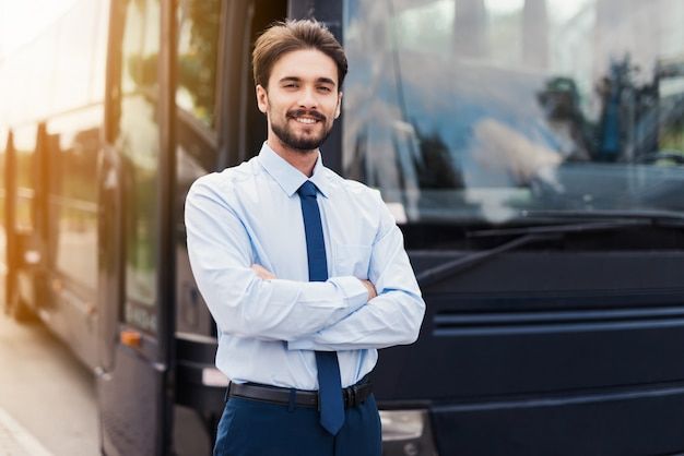 a man standing in front of a bus with his arms crossed and looking at the camera