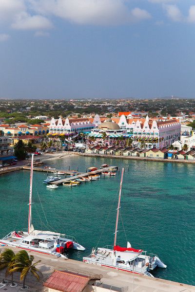 several boats are docked in the water next to some buildings and palm trees on the shore