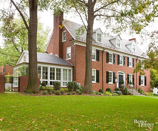 a large red brick house with white trim and windows on the front, surrounded by trees