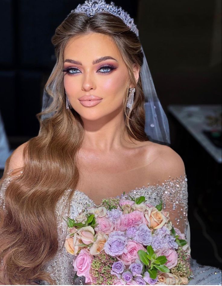 a woman with long hair wearing a bridal gown and holding a bouquet of flowers