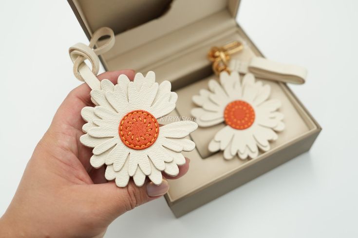 a pair of white and orange daisy earrings in a box with keychain attached