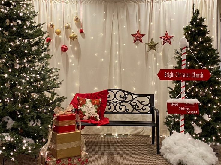 christmas trees and presents are displayed in front of a white curtained room with lights