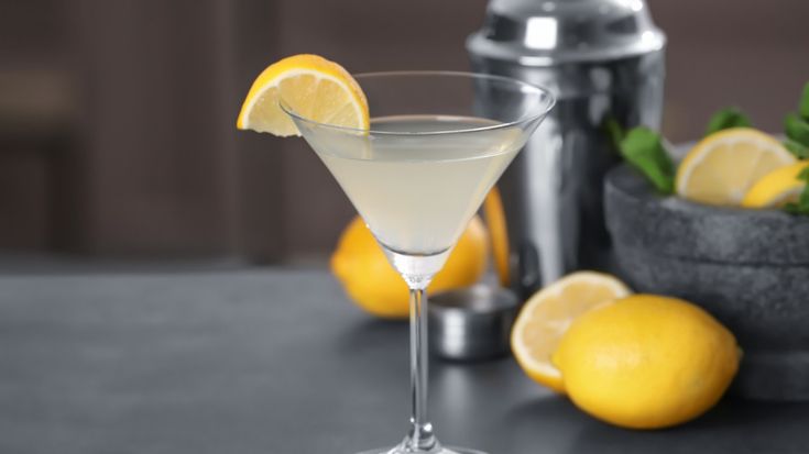 a martini glass filled with white wine and lemons next to a cocktail shaker