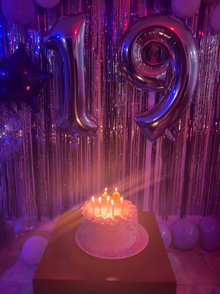 a birthday cake sitting on top of a table in front of balloons and streamers