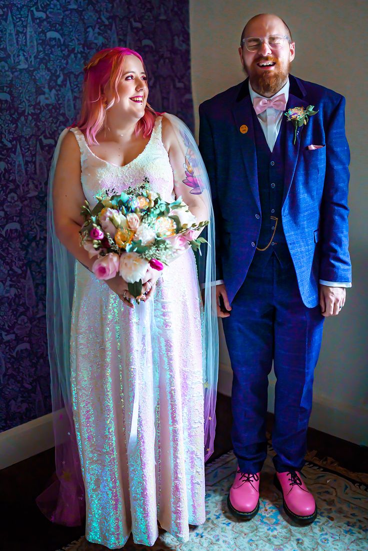 a man and woman standing next to each other in front of a wall with purple walls