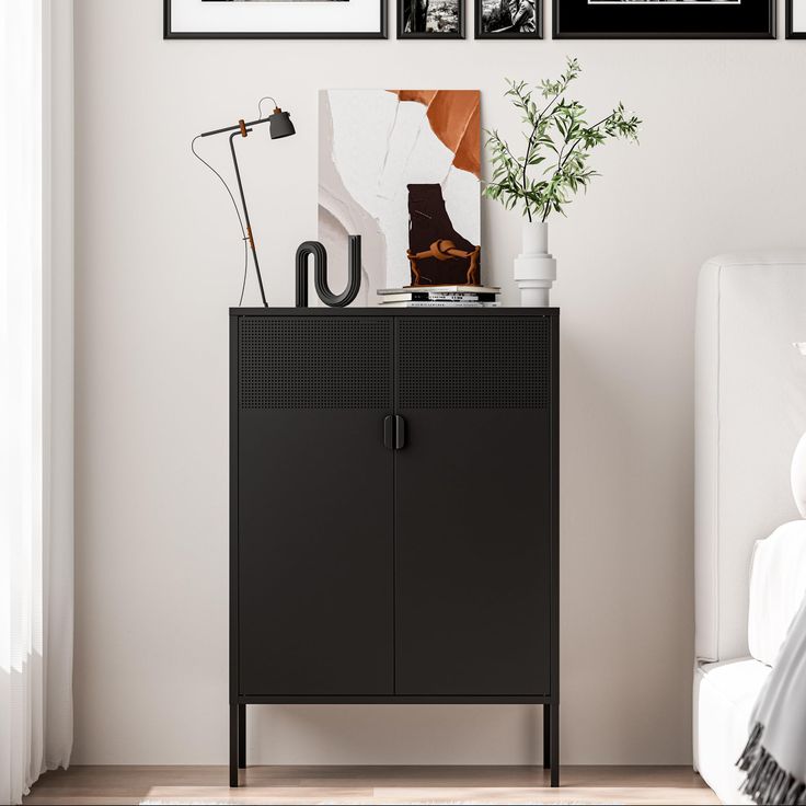 a black cabinet sitting next to a white couch in a room with pictures on the wall