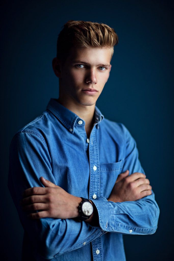 a young man with his arms crossed wearing a blue shirt