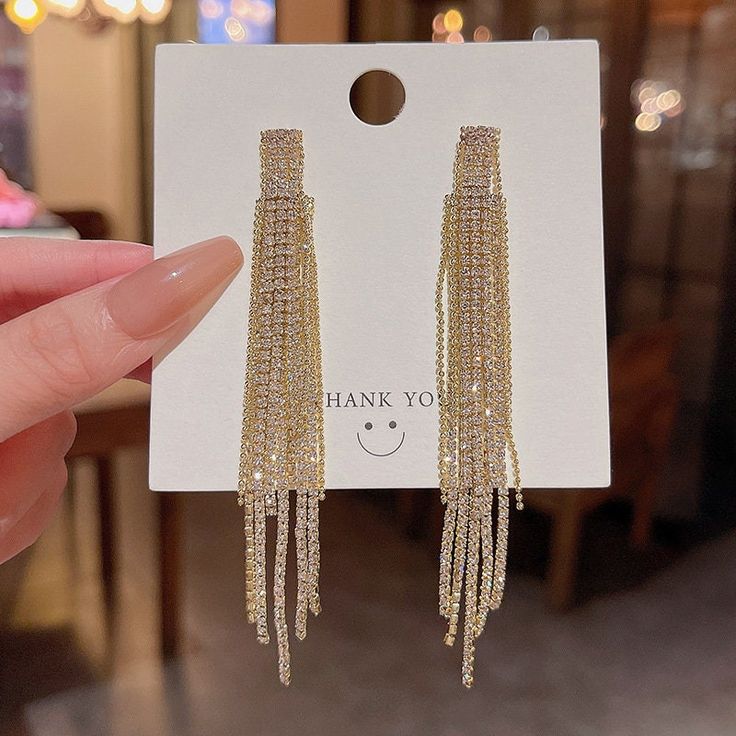 Add some extra shine and glamour to your party outfit with these gorgeous tassel earrings. The beautiful, dangling design is perfect for adding movement and sparkle to your look. The earrings feature a stunning gold colour that will complement any outfit, and the absence of any stones will give them a simple yet elegant look.These earrings are perfect for any occasion, but they are especially fitting for the festive season. They are made of high-quality materials and are sure to be a hit with an Cheap Party Tassel Dangle Earrings, Glamorous Rhinestone Fringe Tassel Earrings For Party, Glamorous Gold Fringe Earrings, Party Tassel Drop Earrings With Rhinestone Fringe, Glamorous Rhinestone Fringe Dangle Tassel Earrings, Glamorous Tassel Drop Earrings, Trendy Gold Crystal Earrings For Wedding, Trendy Gold Tassel Earrings With Fringe, Elegant Gold Chandelier Earrings With Fringe