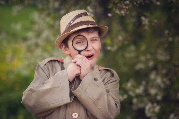 a young boy wearing a hat and holding a magnifying glass