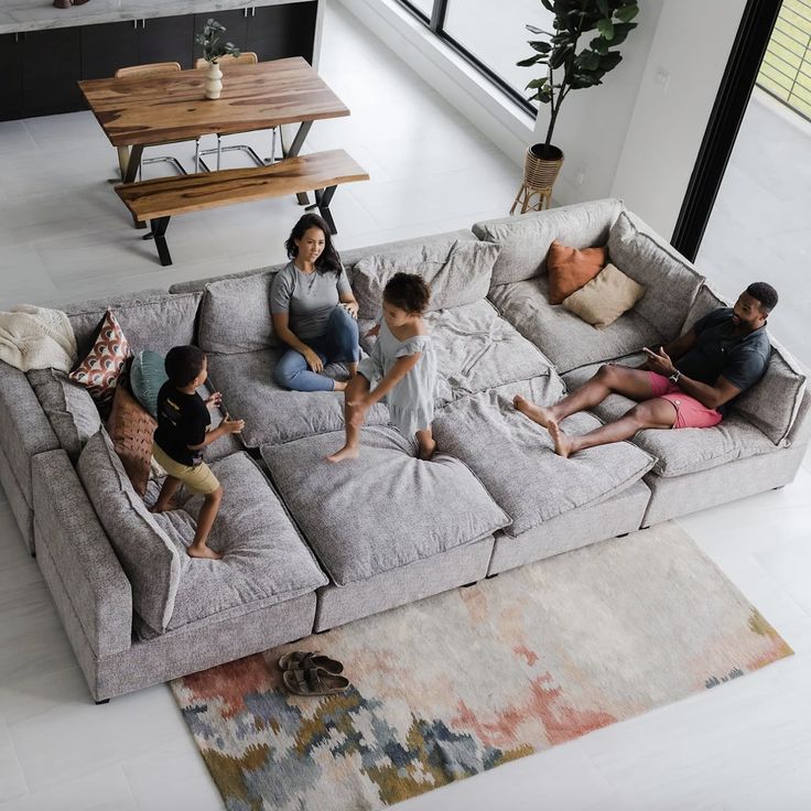 a group of people sitting on top of a couch in a living room next to a coffee table