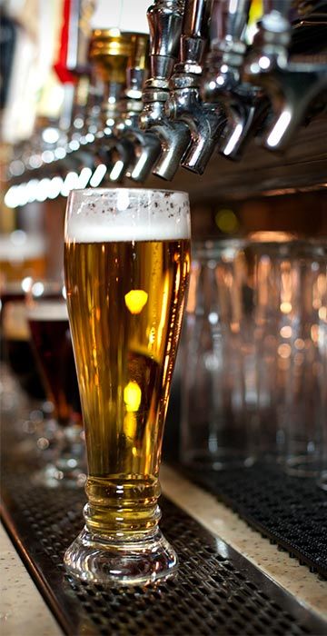 a glass of beer sitting on top of a bar