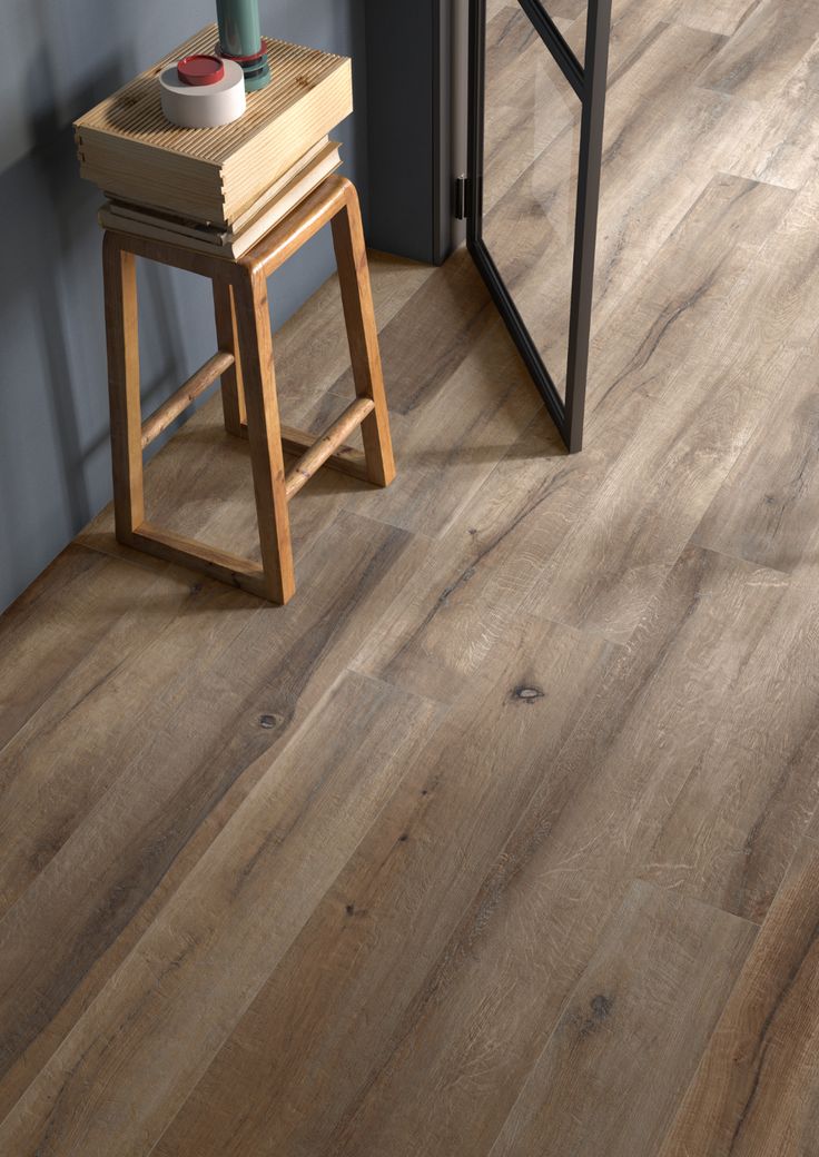 an empty room with wooden floors and a stool next to the door that has a vase on it